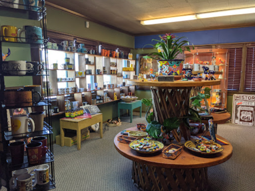 A cozy gift shop featuring colorful mugs, souvenirs, and decorative items displayed on shelves and tables.